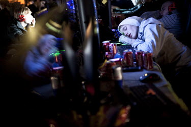 A young person sleeps surrounded by cans of Coca-Cola next to a computer at Dreamhack, a digital festival with the largest LAN (local area network) in the world. 10,544 units were connected to the LAN...