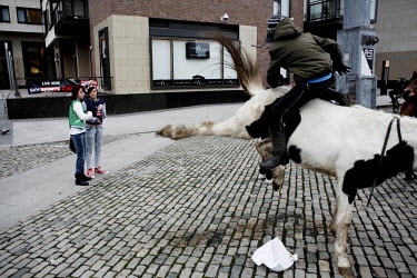 Two girls watch a boy sit on a horse kicking its back legs at Smithfield horse market in central Dublin. This traditional market has now became a place for people from the poor neighbourhoods who cann...
