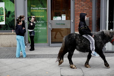 Girls watch a boy ride his small horse at Smithfield horse market in central Dublin. This traditional market has now became a place for people from the poor neighbourhoods who cannot afford to look af...