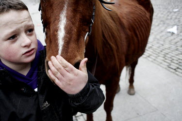 A young boy holds the nose of his horse at Smithfield horse market in central Dublin. This traditional market has now became a place for people from the poor neighbourhoods who cannot afford to look a...
