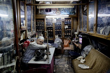 68 year old shoemaker Mounir Addas sits at his desk in his shoe shop at a souk in Aleppo's old town. He opening his shop here in 1956.