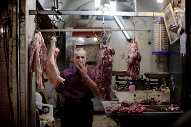 40 year old butcher Yaseen Abu Dah smokes in his meat shop which he has run for 35 years at a souk in Aleppo's old town.