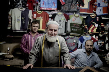 67 year old Jamil Alaf stands with his two sons Essam Alaf and Samir Alaf in their clothes shop at a souk in Aleppo's old town. They work as tailors and the workshop has been in the family since 1954.