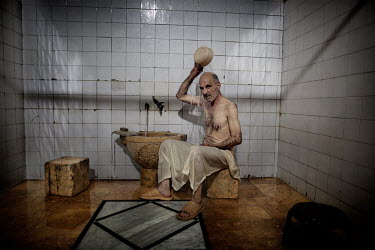 A man washes at a traditional bath, used by locals for hundreds of years. Every evening men arrive for a bath, where they can socialise and smoke.