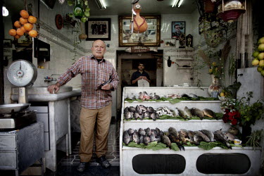 60 year old Ahmed Shawi poses in his fresh fish shop at a souk in Aleppo's old town. He started this business when he was seven years old.