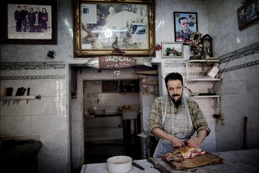 Christian Al-Jedeida smokes as he works in his fresh fish shop at a souk in Aleppo's old town.