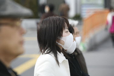 Pedestrians in face masks wait to cross the street at the West Exit of Shinjuku Station. It is a common misconception among foreigners who come to Japan that the people wearing white cotton face masks...