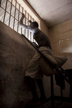 16 year old Maju Daramy looks through the bars of the window of his cell in Pademba Central Prison. He received a 3 year sentence for stealing a phone, a charge he denies.