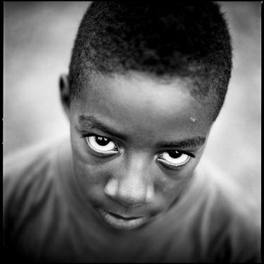 A portrait of a young boy in Joppa, Texas, taken after playing football with his friends.