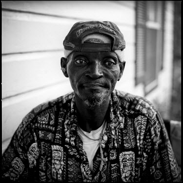 A portrait of James, who sits on the porch outside of his house, Joppa, Texas.