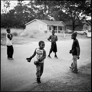 Children play with boxing gloves in the street in Joppa, Texas.