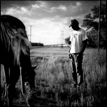 A man stands with his horse in a field in Joppa, Texas.