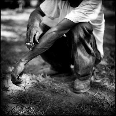 A man smokes a cigarette in his yard. Joppa, Texas.