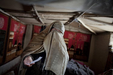 45 year old Pekai, a former Afghan refugee, lives in a cave with her husband and their five children. She shows a picture of her son who is in the Afghan army. ^During the winter, this place is ice co...