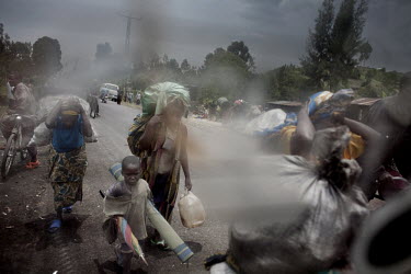 Men, women and children flee along the main road into Goma. They carry essential possessions like mattresses and blankets. Many go to refugee camps, others seek refuge with family and friends in Goma....