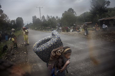 Men, women and children flee along the main road into Goma. They carry essential possessions like mattresses and blankets. Many go to refugee camps, others seek refuge with family and friends in Goma....