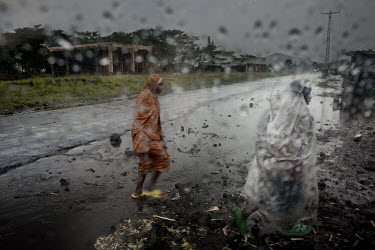 Women flee in the rain along the main road into Goma. More than 100,000 people fled from their homes over a few days when severe fighting broke out between the army and General Nkunda's rebel forces.