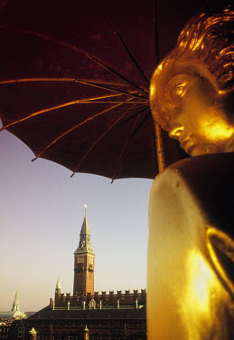 A statue of the Weather Girl (vejrpigen) holding an umbrella by artist Einar Utzon-Frank that forms part of an ornate revolving weather vane on top of the Richshouse in City Hall Square. In the backgr...