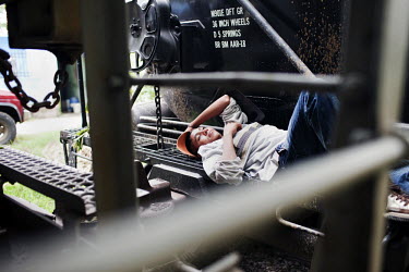 A migrant rests on a coupling for a train in Palenque, Chiapas.