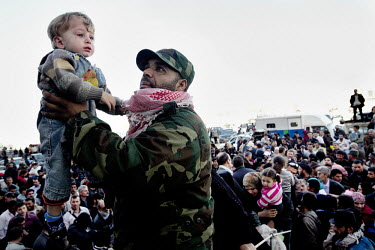 A Libyan soldier holds a child as he helps to process thousands of Syrian refugees as they try to escape Libya at the port in Benghazi. Syria has sent ships to pick up their citizens, but there's only...