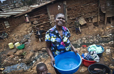 A woman and her son, residents of Kibera, Nairobi's biggest slum, wash clothes next to an open sewer.