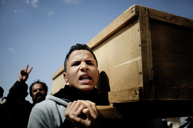 A young man helps to carry a coffin at a mass funeral for six people who died during fighting between Gaddafi's forces and the rebels for the control of the city of Brega. Around 500 people attended t...
