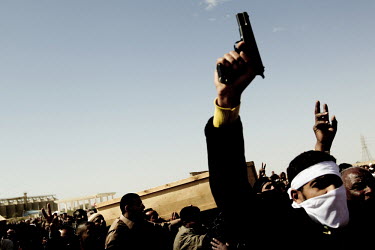 A man fires a gun into the air as a coffin is carried at a mass funeral for six people who died during fighting between Gaddafi's forces and the rebels for the control of the city of Brega. Around 500...