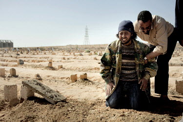 A man mourns at the gravesite after a mass funeral for six people who died during fighting between Gaddafi's forces and the rebels for the control of the city of Brega. Around 500 people attended the...
