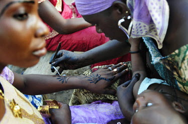 Women have henna designs painted onto their skin in the street in preparation for Eid ul-Fitr, marking the end of Ramadan.
