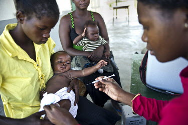 A baby receives a vaccination at a hospital. The hospital was built by oil company Tullow Oil, who drill nearby at the Kigogole oil field.