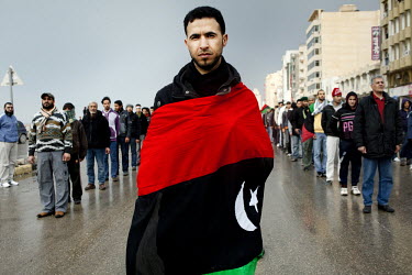 A man wraps a pre Gaddafi Libyan flag around himself as 'The army of rebel volunteers' march through the streets of Benghazi. These young men who have no military background have undergone five days o...