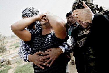 Men mourn at a mass funeral for approximately 20 people who died on the evening of March 4, when a huge deposit of ammunition exploded outside of Benghazi. Rebels claim that it was Gaddafi's forces th...