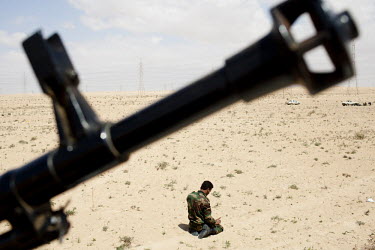 A man prays as he joins the front at Ajdabiya. A gun is seen in the foreground. On 17 February 2011 Libya saw the beginnings of a revolution against the 41 year regime of Col Muammar Gaddafi.