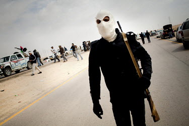 A man holding a gun wears a mask over his face as he joins the front at Ajdabiya. On 17 February 2011 Libya saw the beginnings of a revolution against the 41 year regime of Col Muammar Gaddafi.