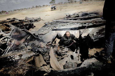 A man searches a destroyed tank, blown up during an air strike against pro Gaddafi forces by the French military while enforcing a no fly zone over Libya. On 17 February 2011 Libya saw the beginnings...