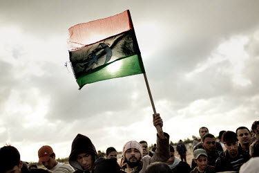 A man holds a flag at a funeral for 20 year old rebel Najm Briwa who was killed during a fight against pro Gaddafi forces. He and some of his comrades were driving in a car towards the front when they...