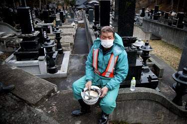 A worker taking a break in a cemetery. He is working on the site of a large pit which is being dug to bury unidentified victims of the Tsunami and earthquake that struck Northern Japan. On 11 March 20...