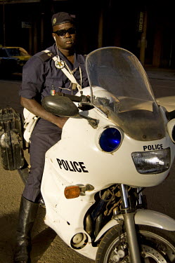 A policeman sits astride a motorbike.