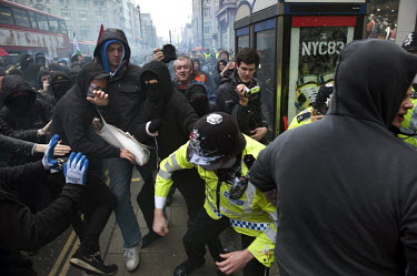 An undercover policeman (blue hood and white trainers) stops protesters attacking a policeman in central London during a march against public sector spending cuts by the coalition government.