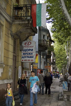A Bulgarian flag hangs from a balcony above a street in Plovdiv.