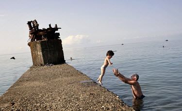 A man plays in the Black Sea with his grandson.