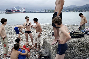 A group of young teenagers cook mussels on the beach in Batumi harbour.