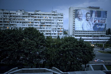 An advertising hoarding for a local television channel featuring its news anchors next to an apartment building in central Chisinau.