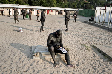 A man with his body coated with black mud from the shores of Lake Techirghiol fills in a crossword puzzle at a resort near the Black Sea. The minerals contained in the mud are considered therapeutic a...