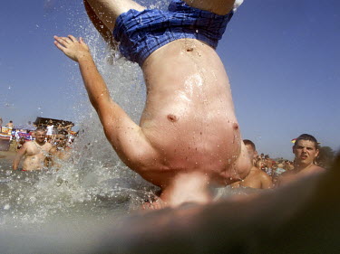 A man somersaults into the sea on a crowded beach at the Black Sea resort of Costinesti.
