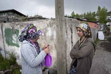 Two women, one knitting, stop for a chat on a street corner in Kars.