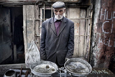 A coal seller stands behind a pair of scales.