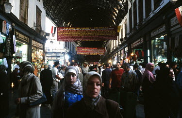 People walk beneath banners, supporting of Lebanon and Hezbollah, hanging in the main entrance to the Al-Hamidiyah Souq.