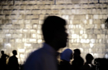 People walk past the walls of the Citadel at night.