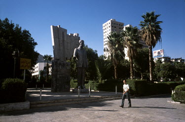 A man walks past a statue of former President Hafez al-Assad in Central Damascus.